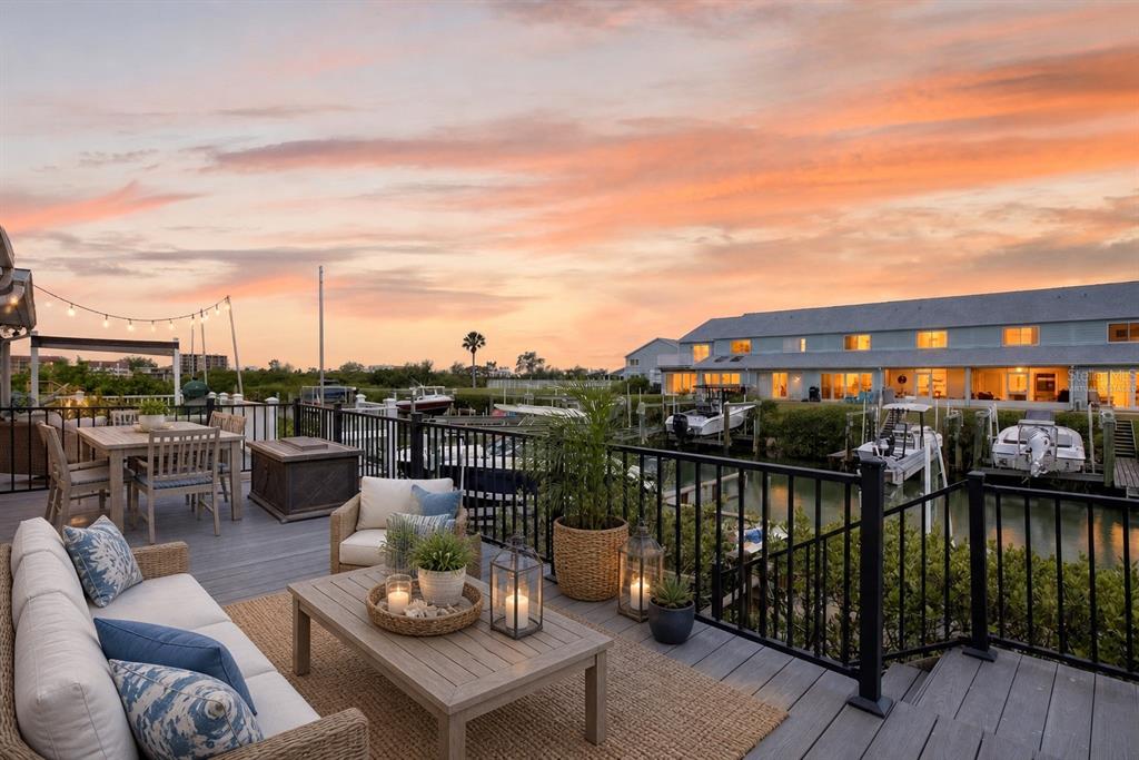 A waterfront deck features outdoor furniture, a dining table, and views of docked boats at sunset — 14617 LORIDAWN DRIVE UNIT 8, SEMINOLE, FL