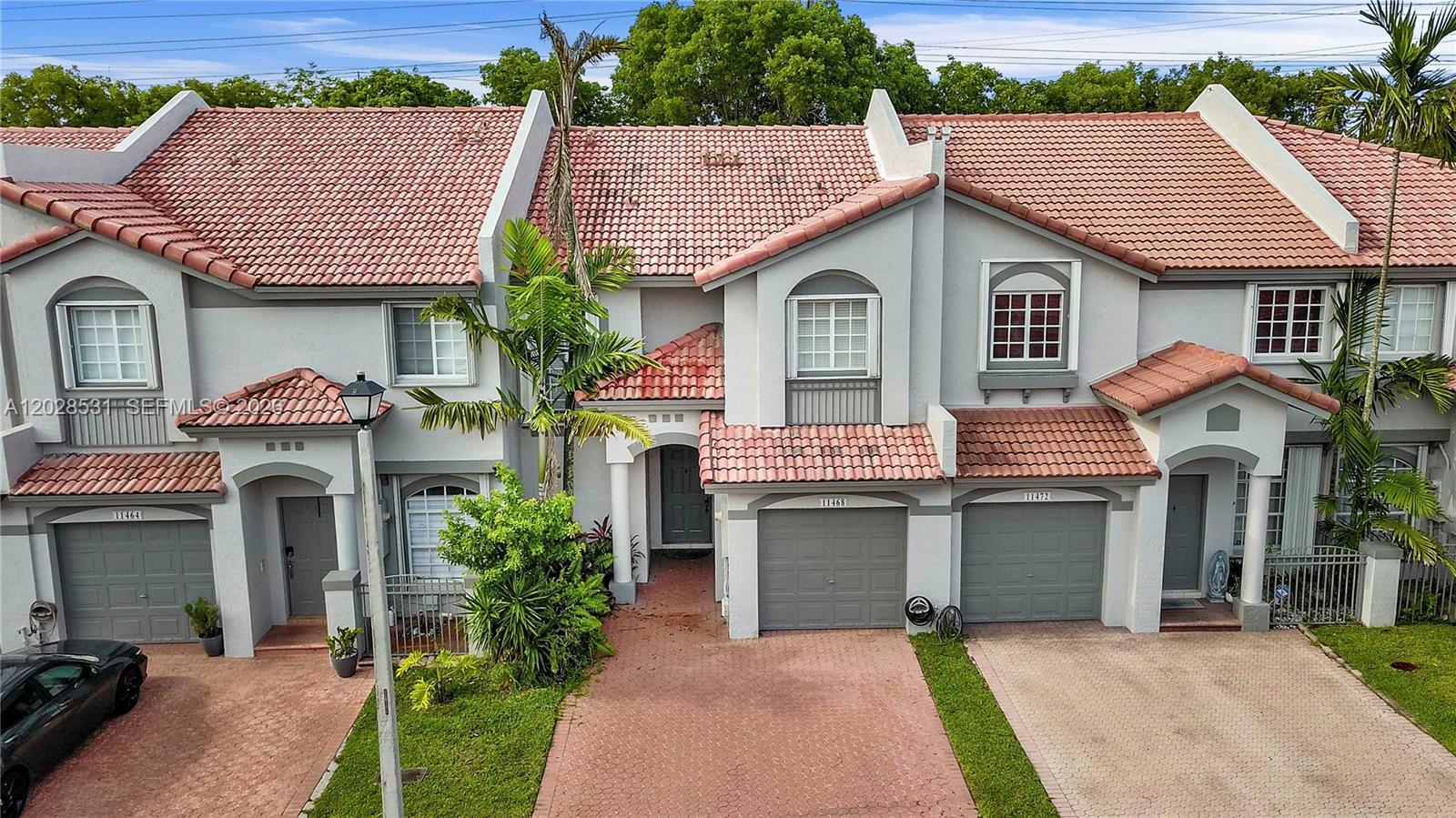 A row of three two-story townhouses with gray stucco walls and red tile roofs — 11468 NW 50th Ter, Doral FL 33178, DORAL, FL