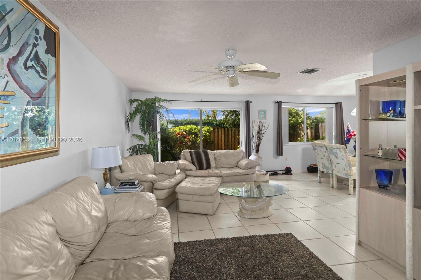 A living room features white leather furniture, a glass coffee table, and tile flooring — 11468 NW 50th Ter, Doral FL 33178, DORAL, FL