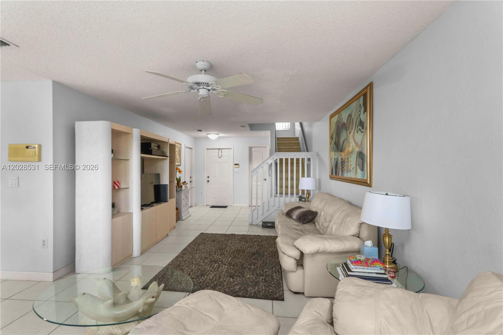 A living room features light tile floors, a ceiling fan, a staircase, and beige furniture — 11468 NW 50th Ter, Doral FL 33178, DORAL, FL