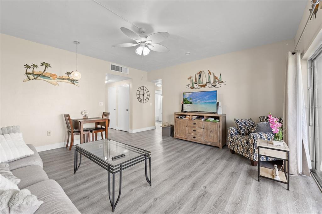 A living room with light wood-look flooring, a glass coffee table, and a dining area — 55 SEA PARK BOULEVARD UNIT 204, SATELLITE BEACH, FL