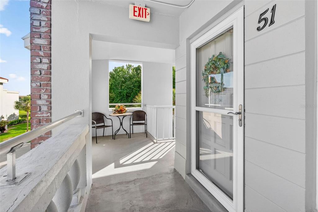An outdoor balcony features a small table with two chairs, a screen door, and unit 51 — 2461 RHODESIAN DRIVE UNIT 51, CLEARWATER, FL