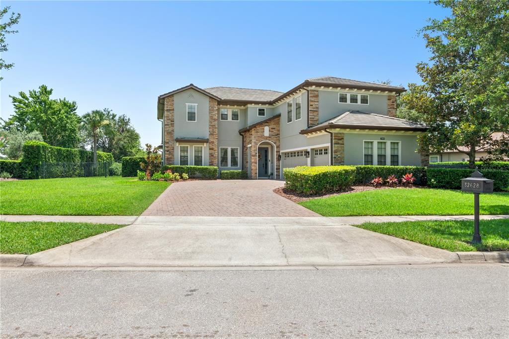 A two-story house with a stone facade, a brick driveway, and a manicured lawn — 32628 VIEW HAVEN LANE, SORRENTO, FL