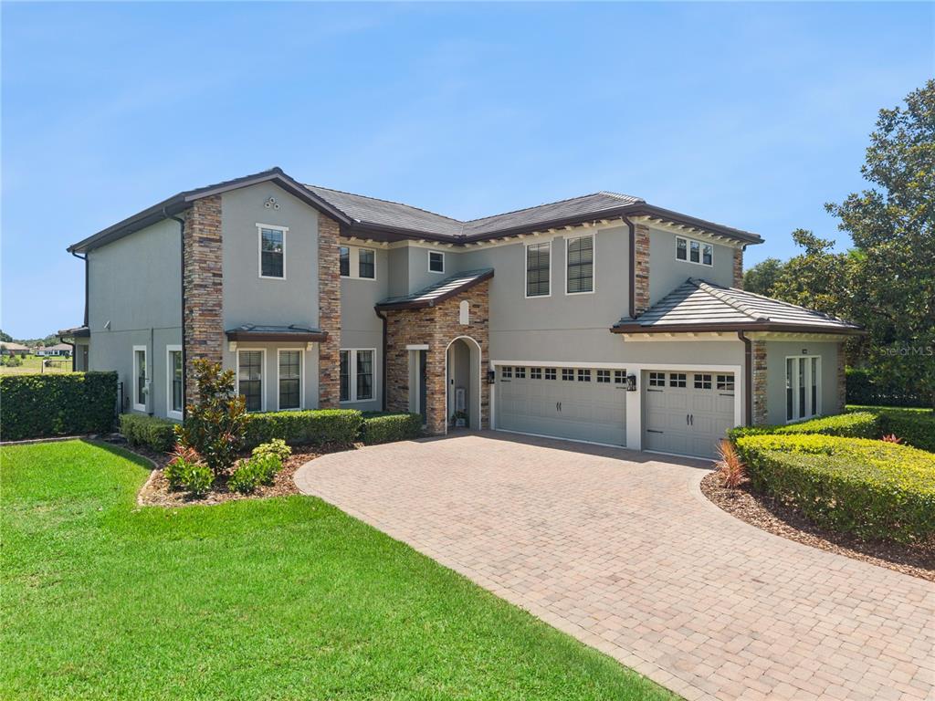 A two-story house with a stone facade, gray stucco, and a brick paver driveway — 32628 VIEW HAVEN LANE, SORRENTO, FL