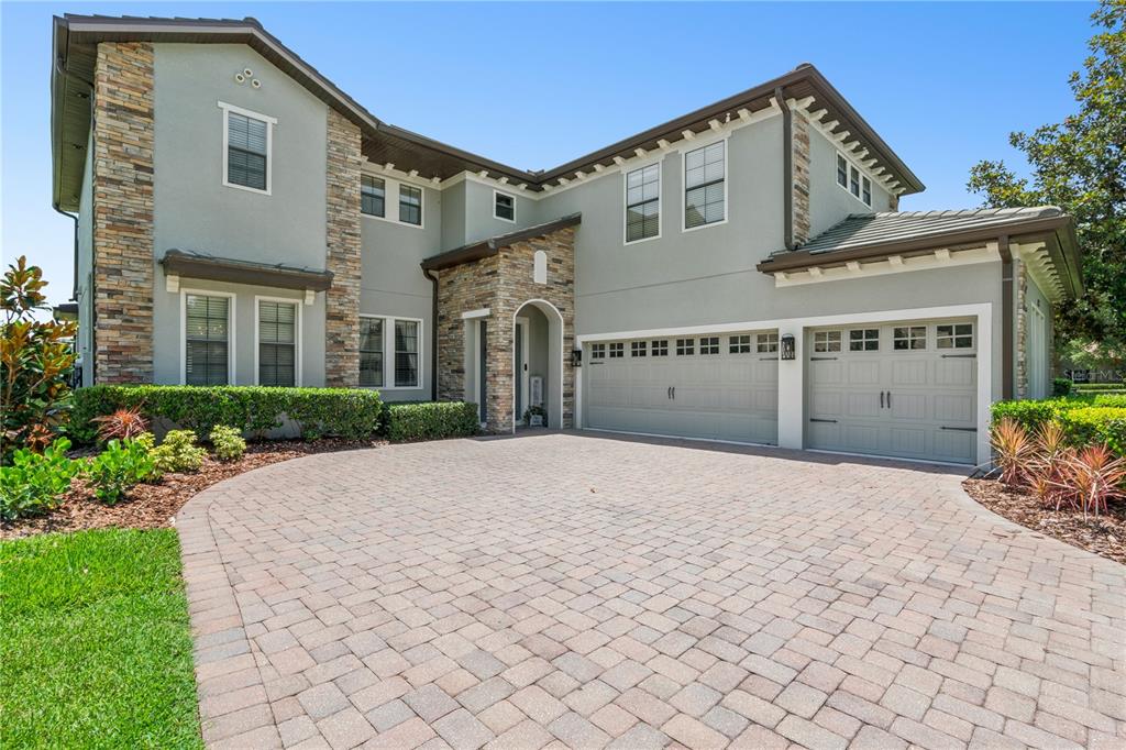 A two-story house features a stone facade, a paved driveway, and an attached three-car garage — 32628 VIEW HAVEN LANE, SORRENTO, FL