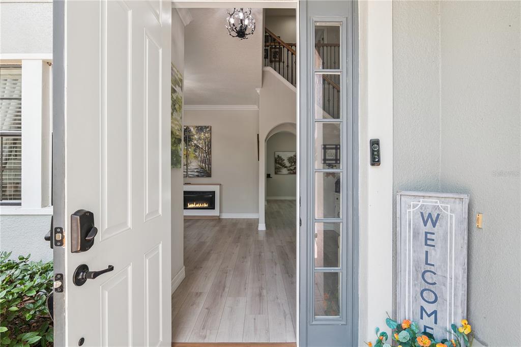 An open front door reveals a foyer with light wood flooring and a staircase — 32628 VIEW HAVEN LANE, SORRENTO, FL