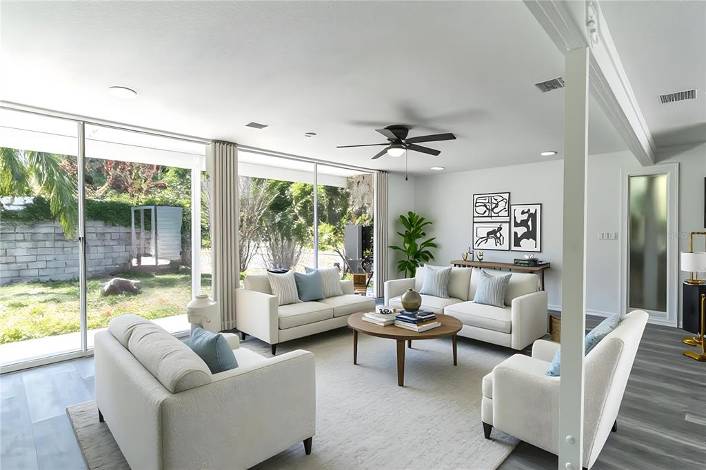 A bright living room features white sofas, a round wooden coffee table, and large sliding doors — 1558 DREXEL AVENUE NE, WINTER HAVEN, FL