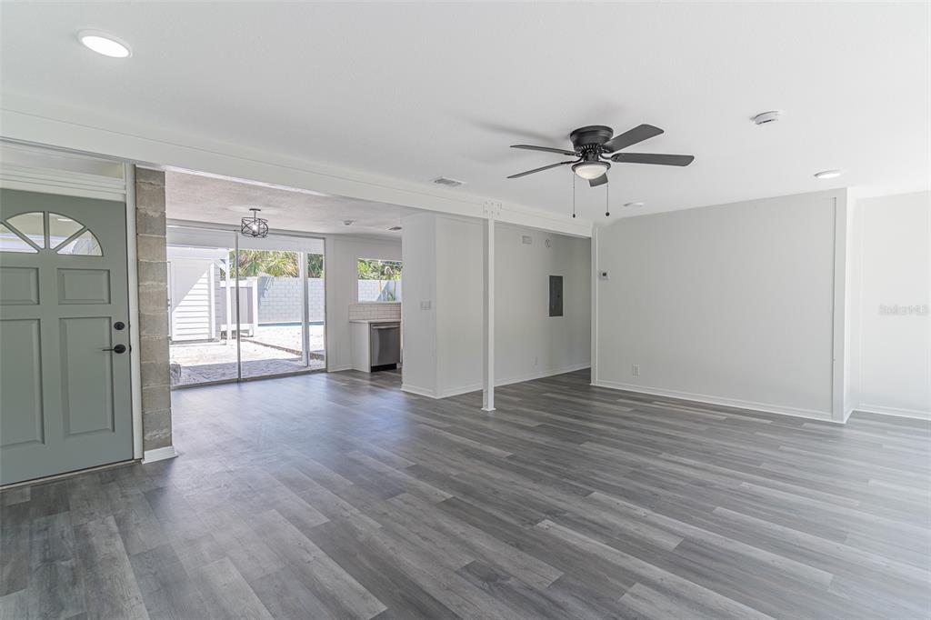 A living area with gray wood-look flooring, a ceiling fan, and a sliding glass door — 1558 DREXEL AVENUE NE, WINTER HAVEN, FL