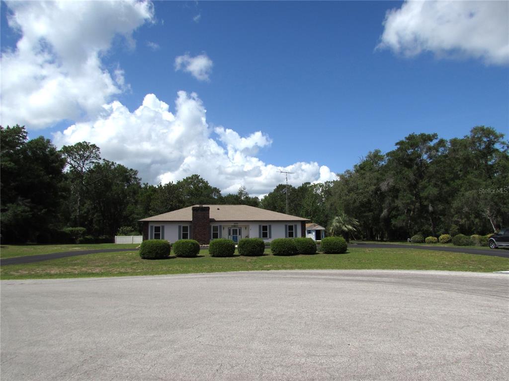 A single-story house with a brick chimney sits behind a circular driveway and lawn — 20620 SW 97TH PLACE, DUNNELLON, FL