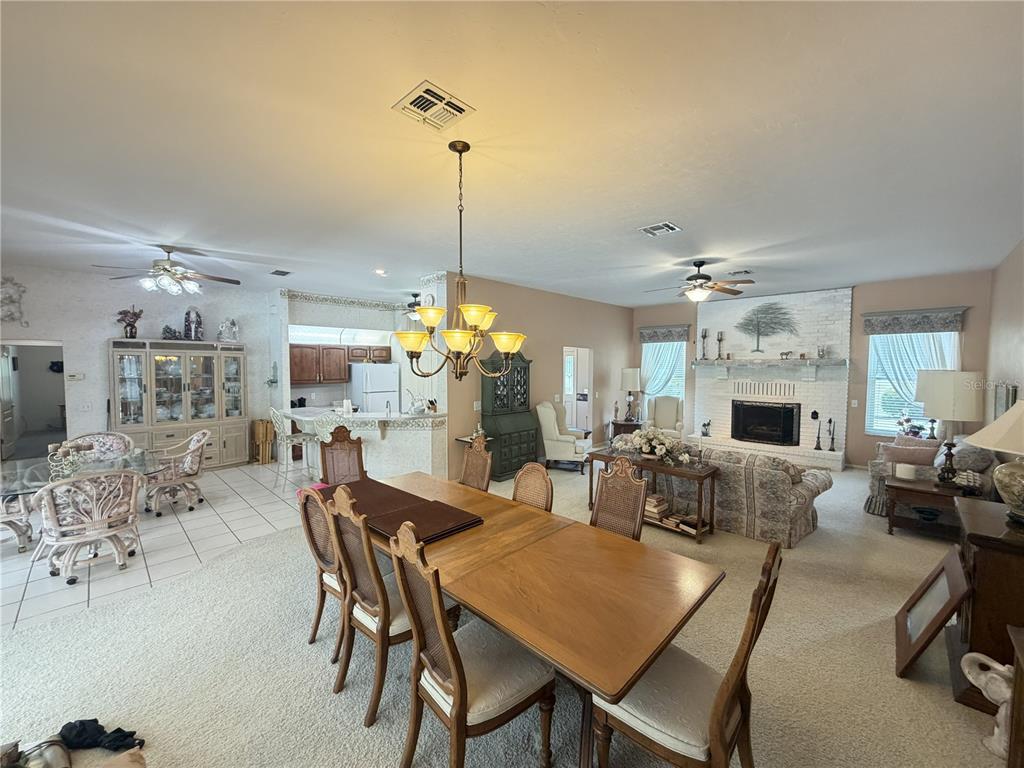 A spacious open-concept living and dining area features a fireplace, chandelier, and tile flooring — 20620 SW 97TH PLACE, DUNNELLON, FL