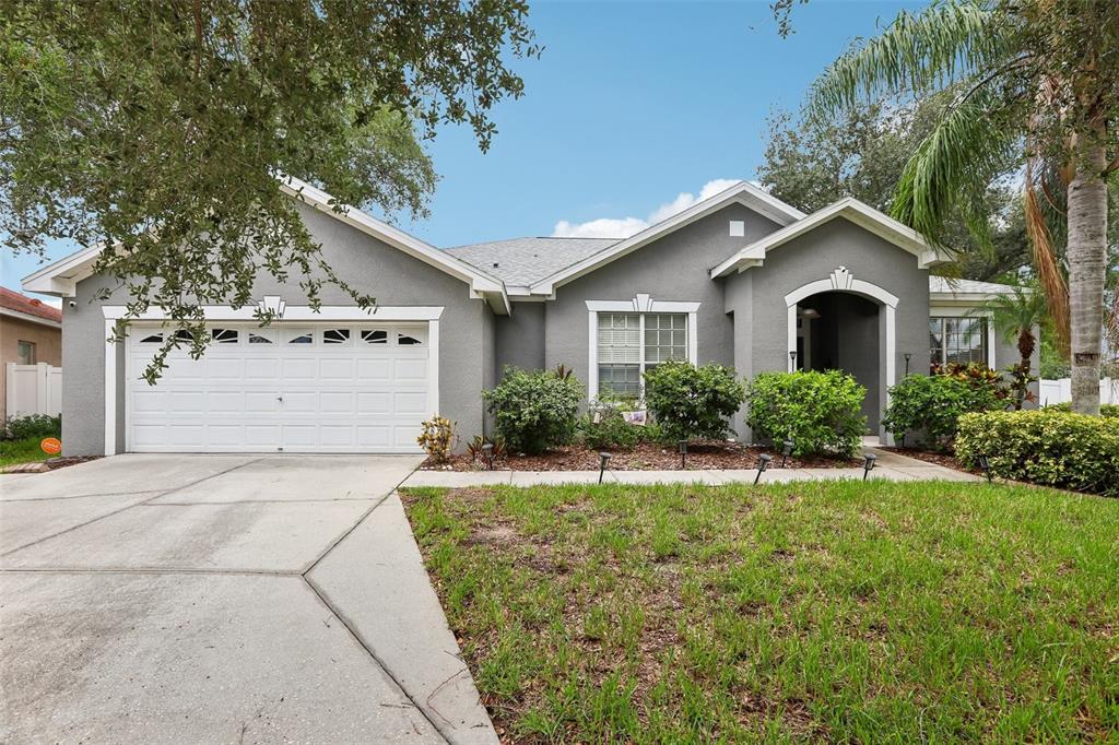 A gray single-story house with a two-car garage, white trim, and a landscaped front yard — 12517 SAFARI LANE, RIVERVIEW, FL