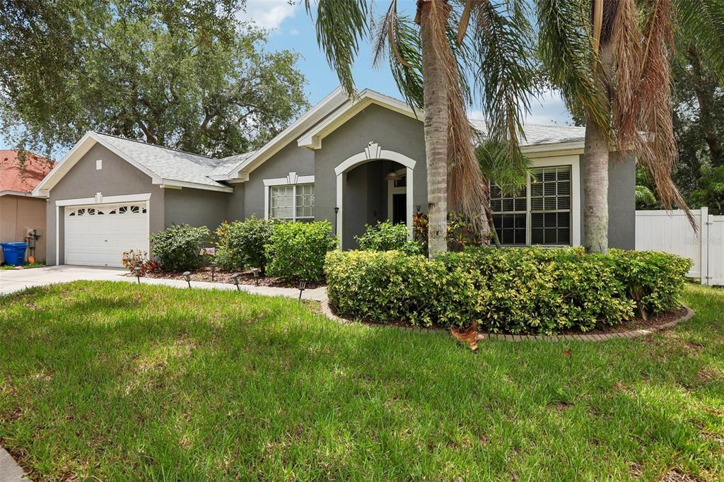 A single-story gray house with a two-car garage, arched entryway, and landscaped front yard — 12517 SAFARI LANE, RIVERVIEW, FL
