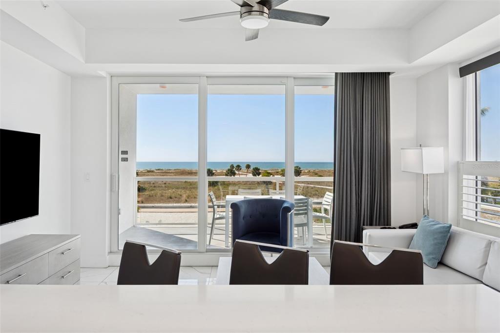 A bright living room features a view of the beach through large sliding glass doors — 11500 GULF BOULEVARD UNIT 313, TREASURE ISLAND, FL