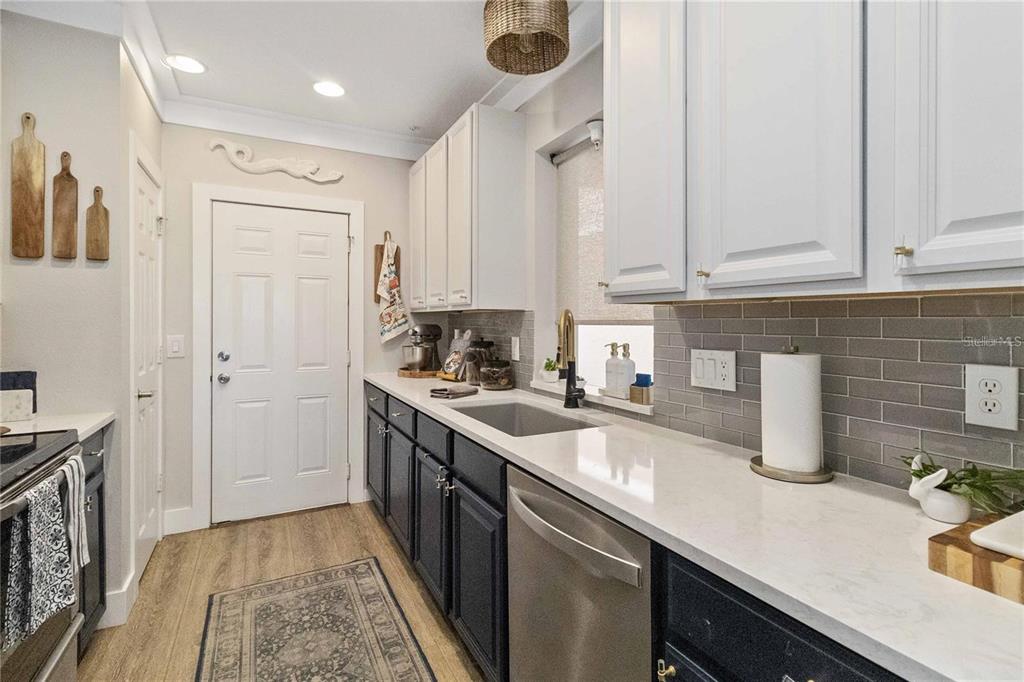 A kitchen features white upper cabinets, dark lower cabinets, a stainless steel dishwasher, and countertops — 7242 HAMILTON ROAD, BRADENTON, FL