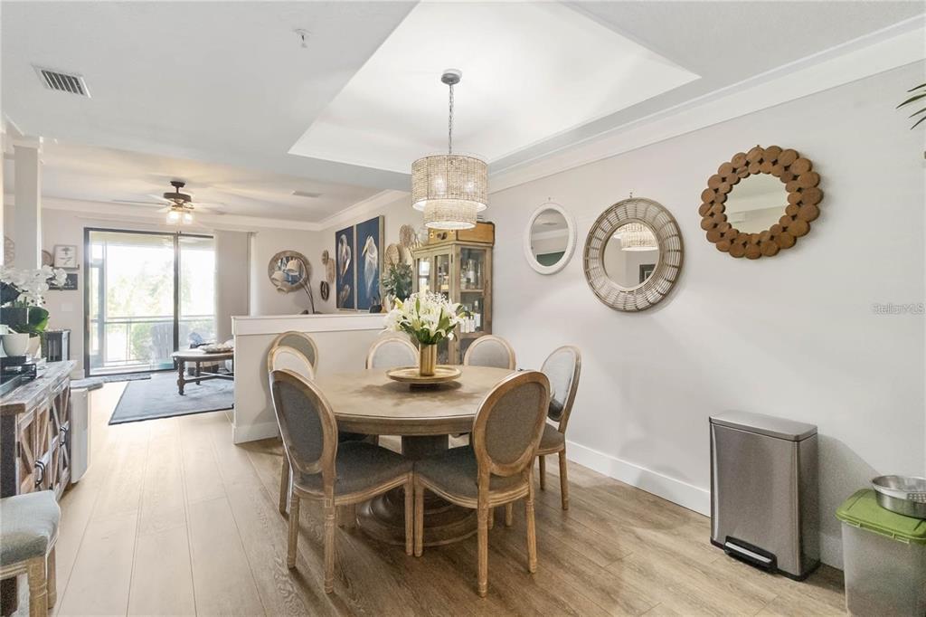 A dining area features a round wooden table, upholstered chairs, and decorative wall mirrors — 7242 HAMILTON ROAD, BRADENTON, FL