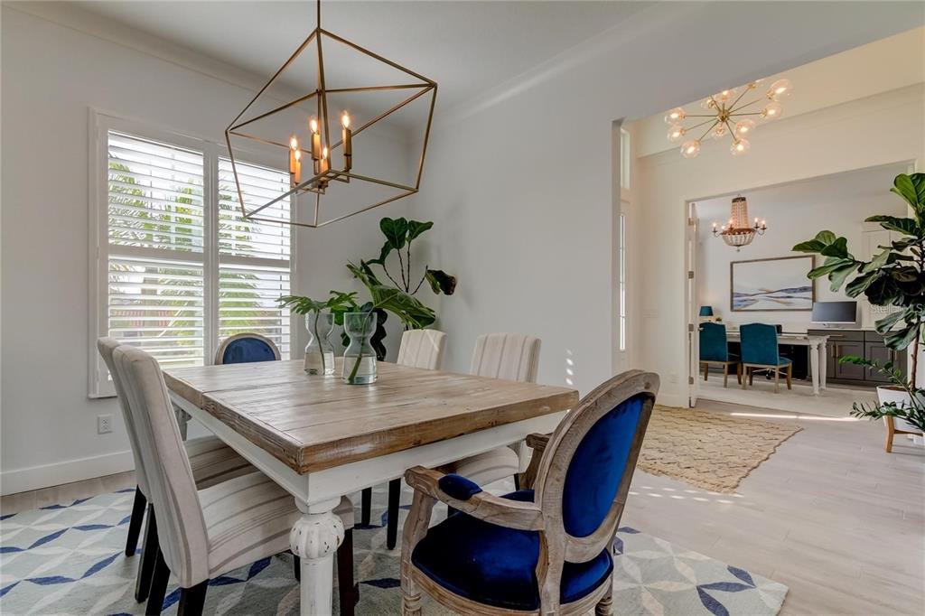 A dining room features a wooden table, blue velvet chairs, and a geometric pendant light — 6706 BURLINGTON AVENUE, ST PETERSBURG, FL