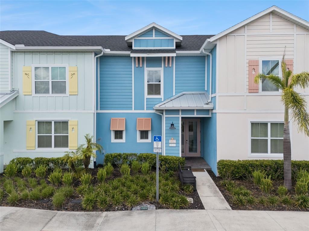 A multi-story building exterior features blue and white siding, a metal roof, and landscaping — 8201 SURF STREET, KISSIMMEE, FL