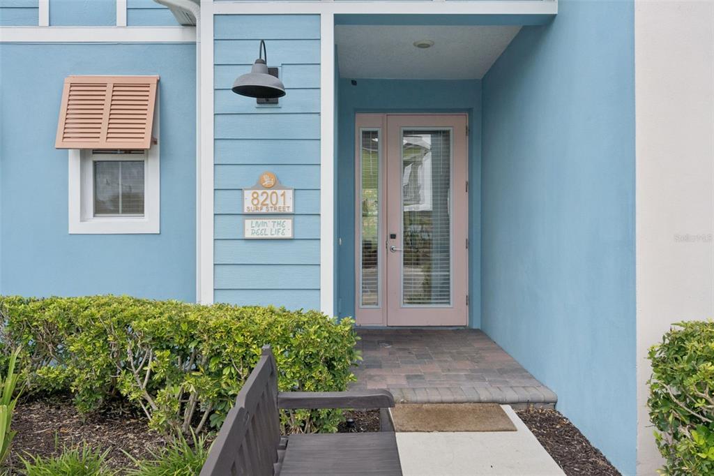 The exterior of a blue house features a pink front door and a wooden bench — 8201 SURF STREET, KISSIMMEE, FL