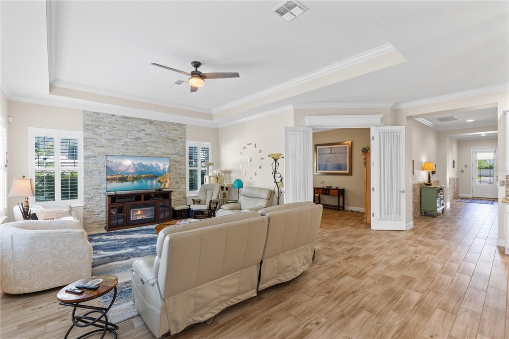 A living room features a stone fireplace, a ceiling fan, and light-colored tile flooring — 7838 DAUSSET STREET, ORLANDO, FL