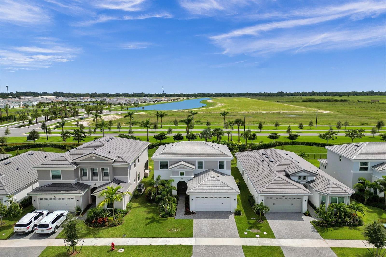 An aerial view shows three suburban houses with gray tile roofs and paved driveways — 5416 Macoon Way, FL 33470, FL