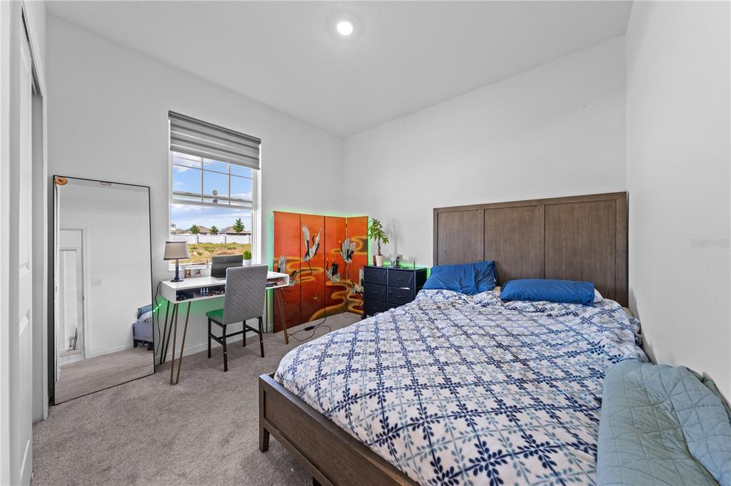A bedroom features a bed, a desk, a floor mirror, and a decorative folding screen — 425 SILVER PALM DRIVE, HAINES CITY, FL