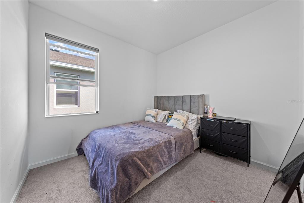 A bedroom features a gray upholstered bed, a black dresser, and a window with blinds — 425 SILVER PALM DRIVE, HAINES CITY, FL