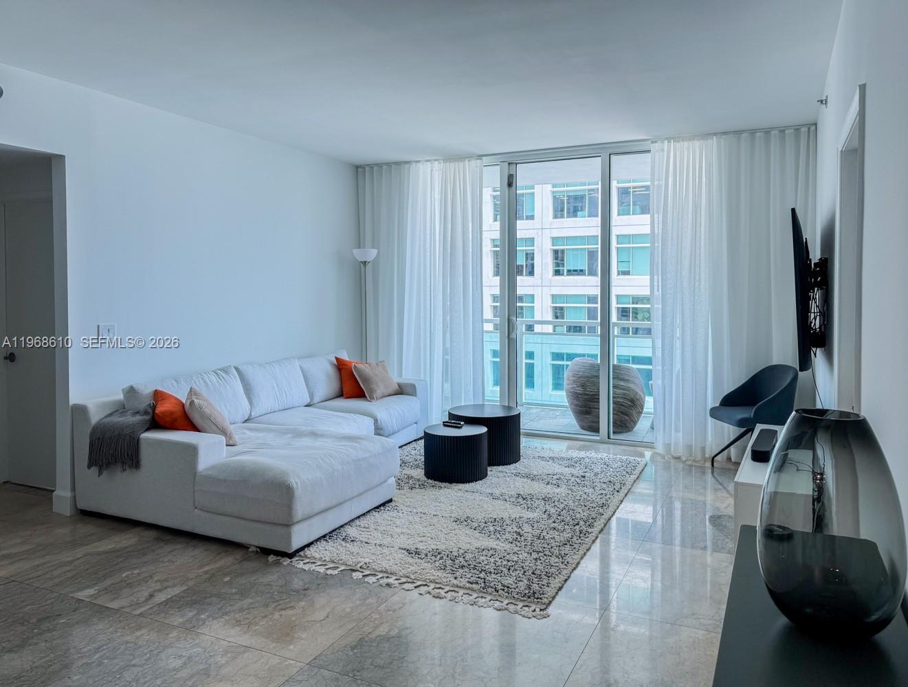 A modern living room features a white sectional sofa, two round tables, and floor-to-ceiling windows — 950 Brickell Bay Dr # 1504, Miami FL 33131, MIAMI, FL