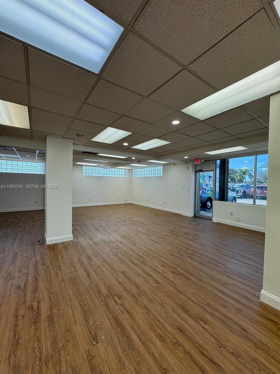 An empty commercial space features wood-look flooring, a drop ceiling with recessed lighting, and glass-block windows — 4201 Palm Ave, Hialeah FL 33012, HIALEAH, FL