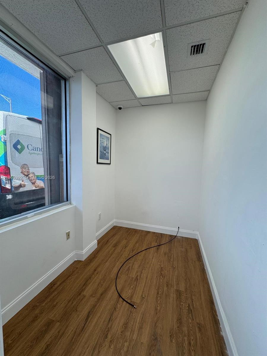 An empty office room features wood-look flooring, white walls, a drop ceiling, and a window — 4201 Palm Ave, Hialeah FL 33012, HIALEAH, FL
