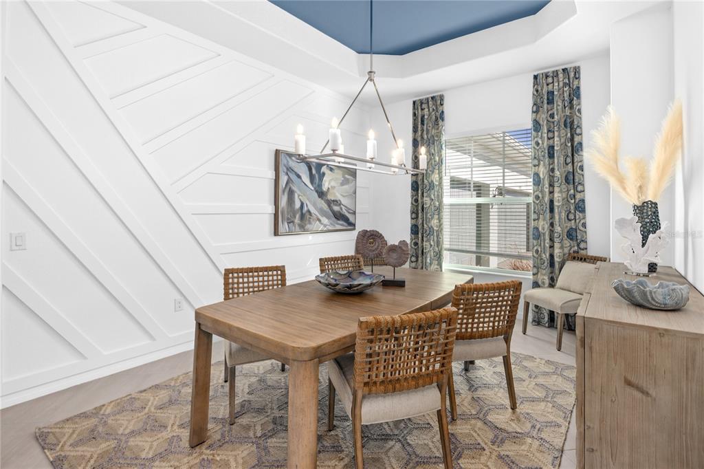 A dining room features a geometric accent wall, a blue tray ceiling, and wooden furniture — 18845 CHERRYSTONE WAY, LAKEWOOD RANCH, FL