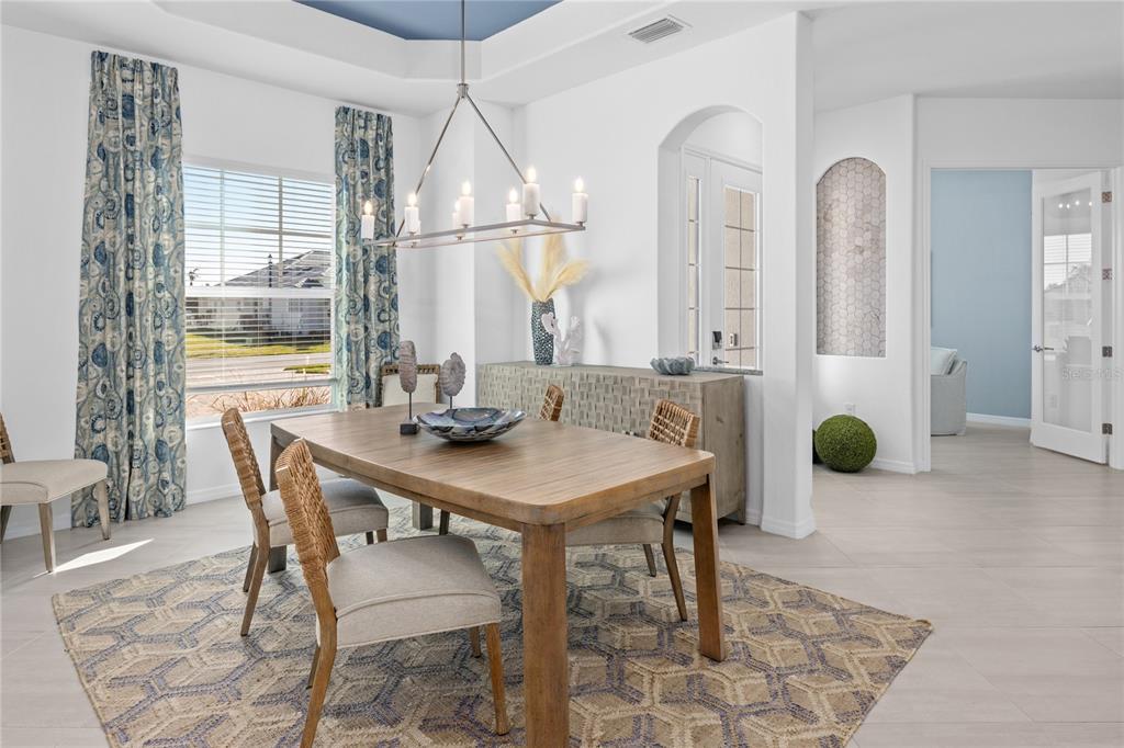 A dining room features a wooden table, woven chairs, a patterned rug, and a chandelier — 18845 CHERRYSTONE WAY, LAKEWOOD RANCH, FL