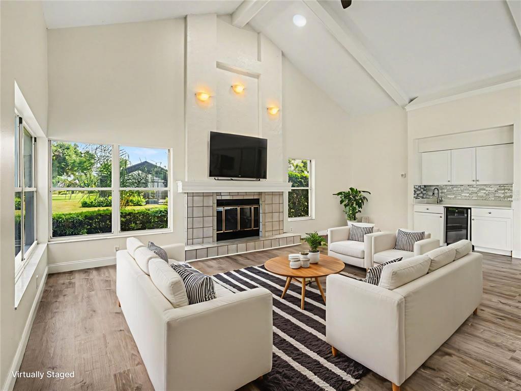 A living room features a vaulted ceiling, a fireplace with a television, and white furniture — 7505 WEEPING WILLOW BOULEVARD, SARASOTA, FL