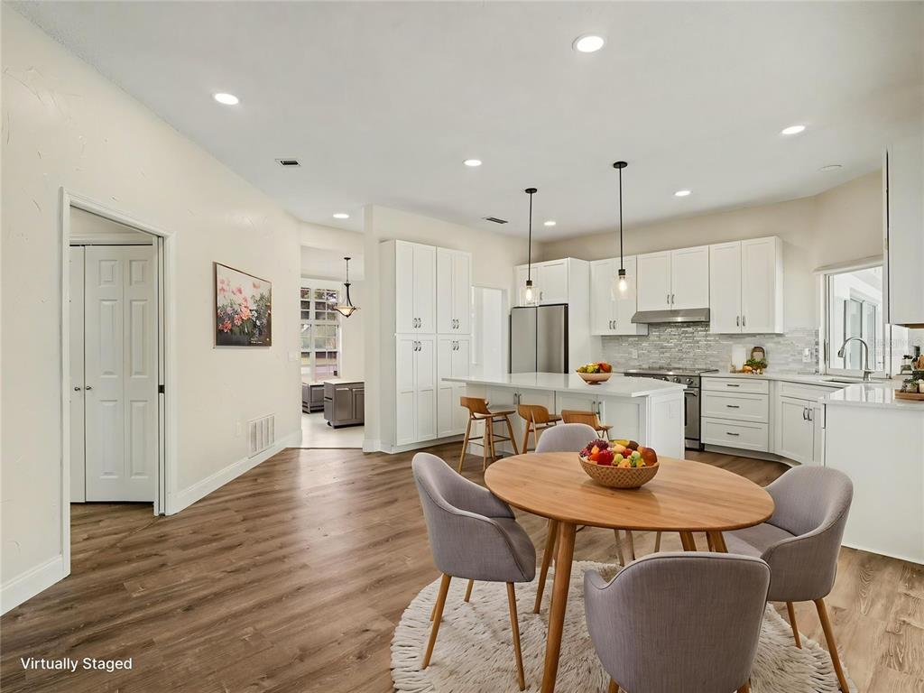A kitchen and dining area feature white cabinetry, a center island, and wood-look flooring — 7505 WEEPING WILLOW BOULEVARD, SARASOTA, FL