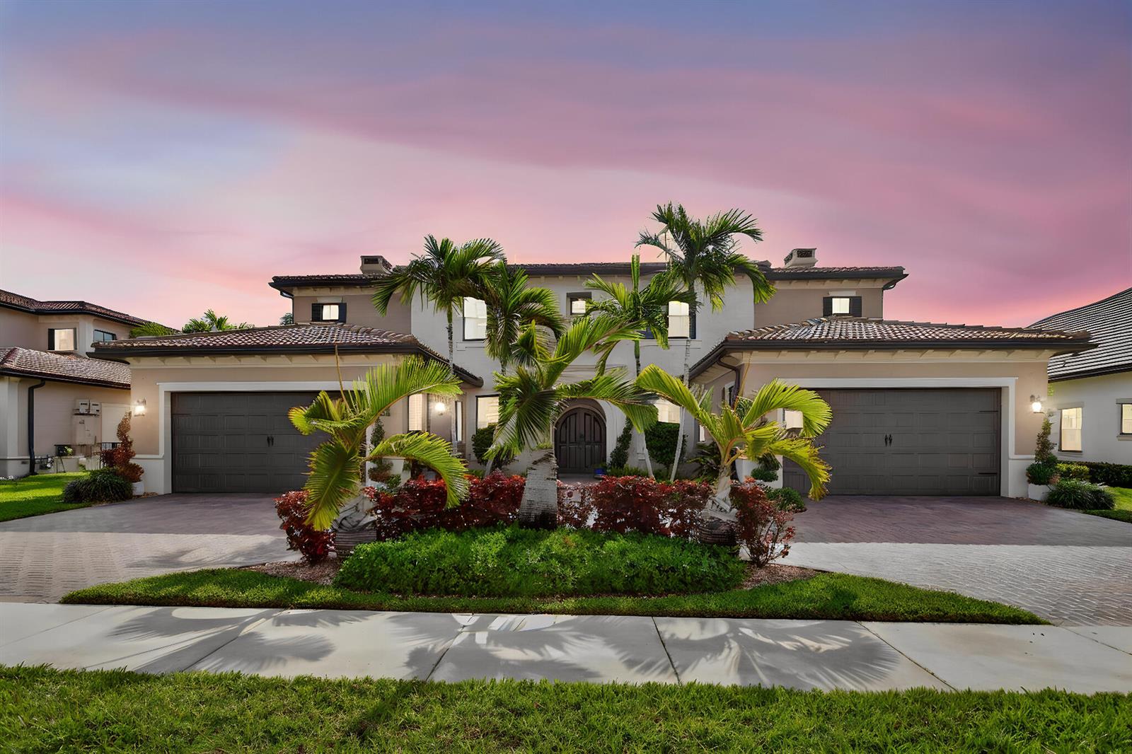 A two-story house with two garages and palm trees in the front yard at sunset — 9080 Vista Way, Parkland FL 33076, PARKLAND, FL