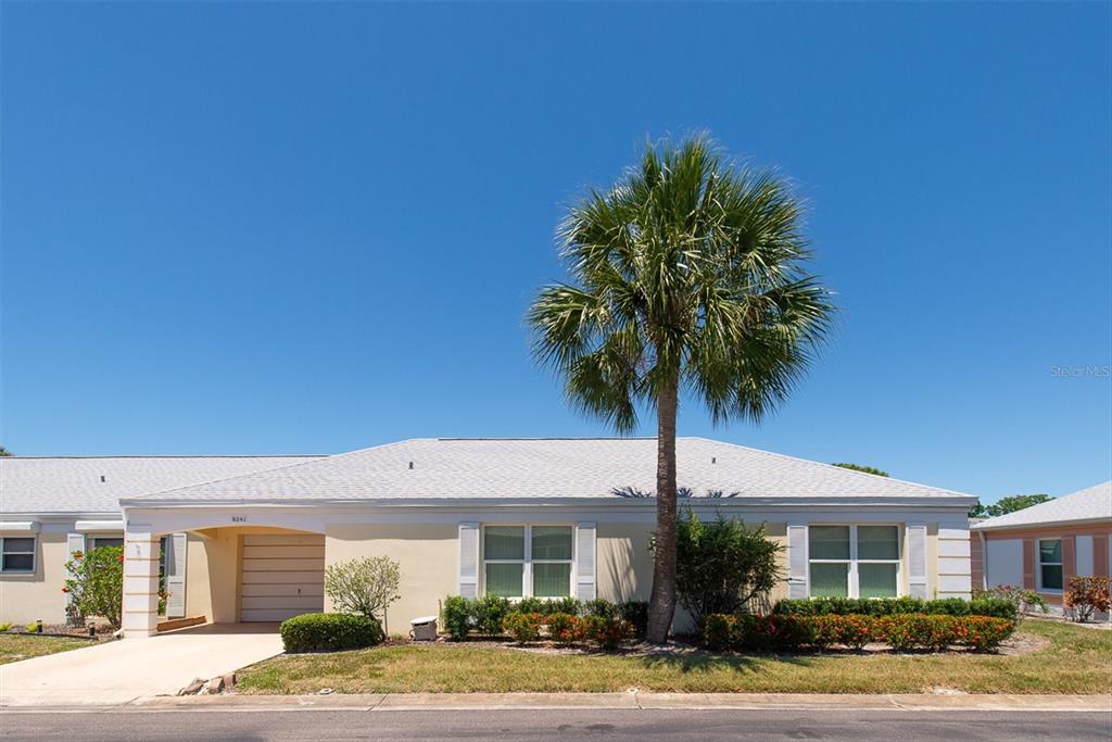 A single-story house with a light yellow exterior, a palm tree, and a paved driveway — 8241 BRENTWOOD ROAD UNIT 8241, SEMINOLE, FL