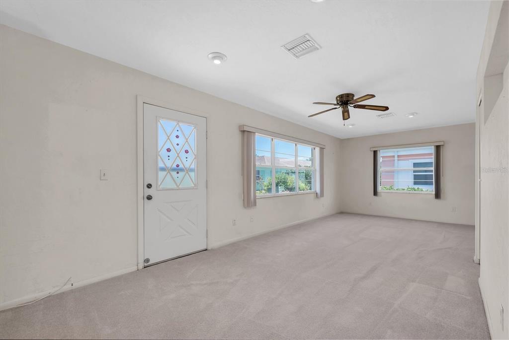 An empty room with beige carpet, white walls, a ceiling fan, and two windows — 8241 BRENTWOOD ROAD UNIT 8241, SEMINOLE, FL