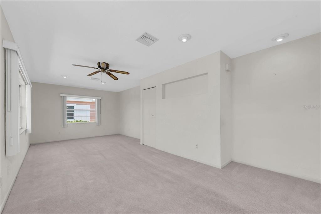 An empty room with beige carpet, white walls, a ceiling fan, and a recessed wall niche — 8241 BRENTWOOD ROAD UNIT 8241, SEMINOLE, FL