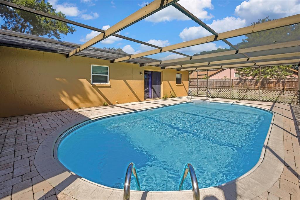 An outdoor swimming pool with a screened enclosure and a paved deck area — 2441 DUSTIN CIRCLE, SPRING HILL, FL