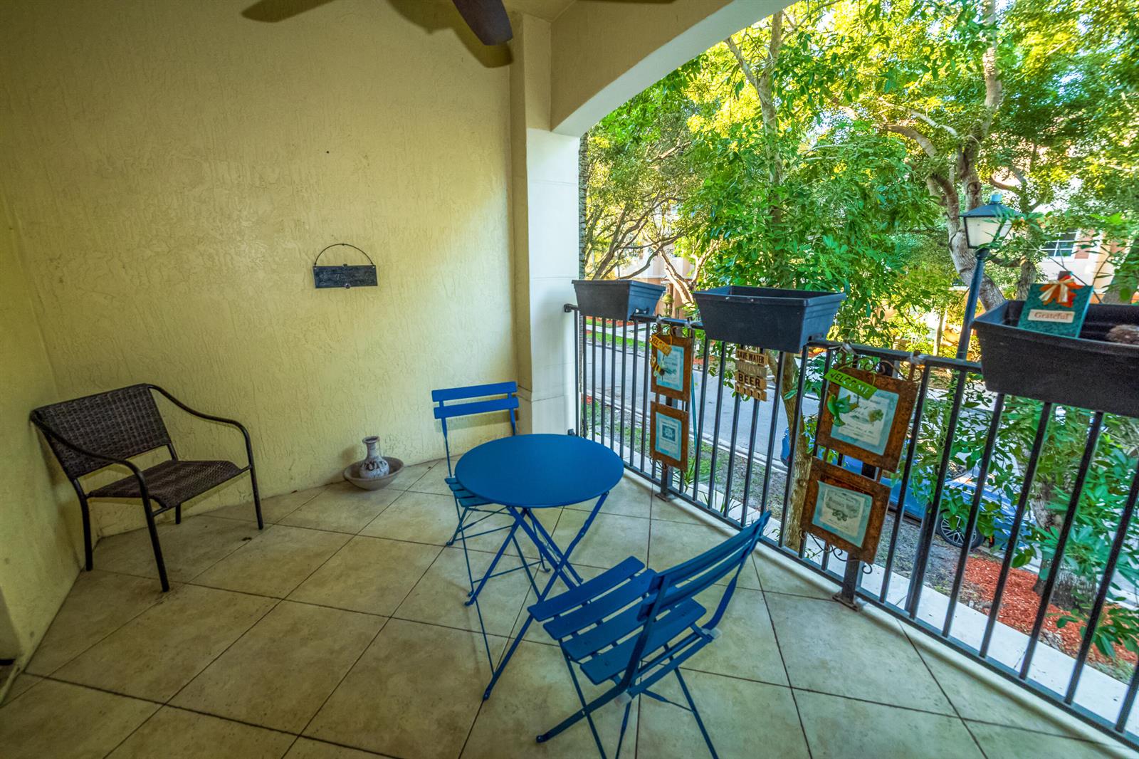 A covered balcony features tile flooring, a blue bistro set, and decorative planters on the railing — 4574 Danson Way, Delray Beach FL 33445, DELRAY BEACH, FL