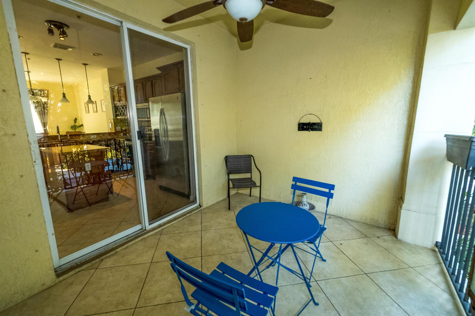 A covered patio features a blue bistro set, a separate chair, and sliding glass doors — 4574 Danson Way, Delray Beach FL 33445, DELRAY BEACH, FL