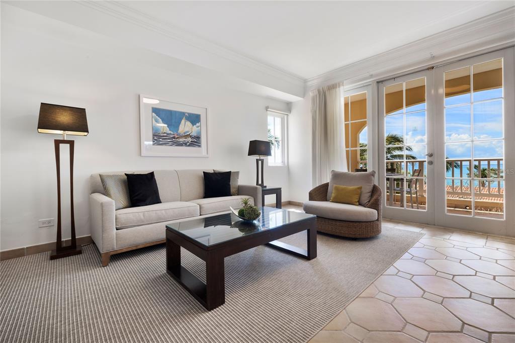 A living room features a sofa, glass coffee table, armchair, and glass doors overlooking the ocean — 1000 EL CONQUISTADOR AVE UNIT 5310, FAJARDO, PR