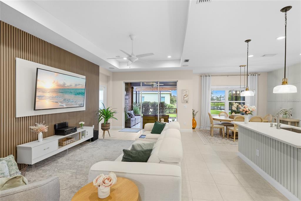 An open-concept living room and dining area features a slatted wood wall and tile flooring — 10601 FALLING LEAF COURT, PARRISH, FL