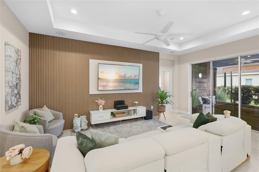 A living room features a slatted wood accent wall, a white media console, and furniture — 10601 FALLING LEAF COURT, PARRISH, FL