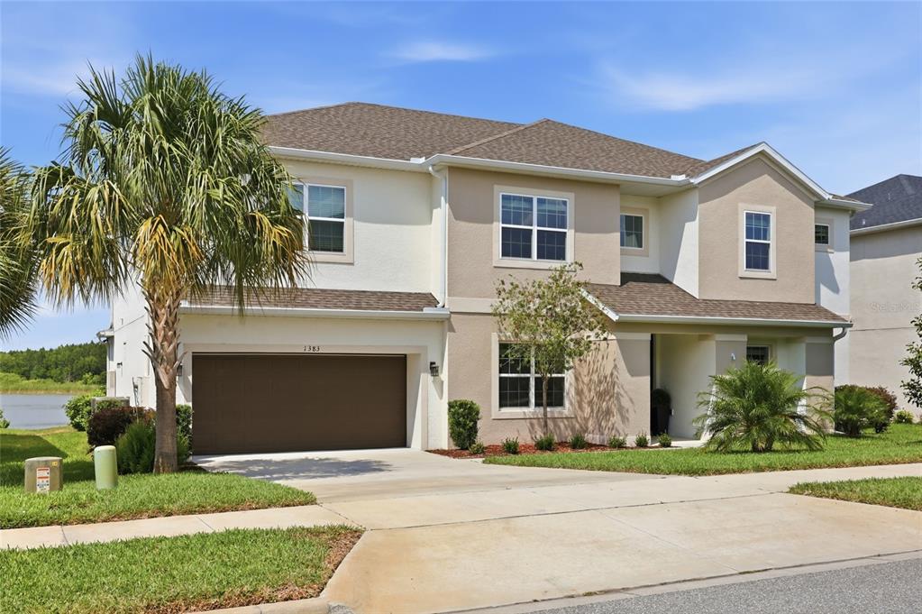 A two-story suburban house with a brown garage, beige stucco exterior, and a palm tree — 1383 WATERVIEW RIDGE CIRCLE, APOPKA, FL