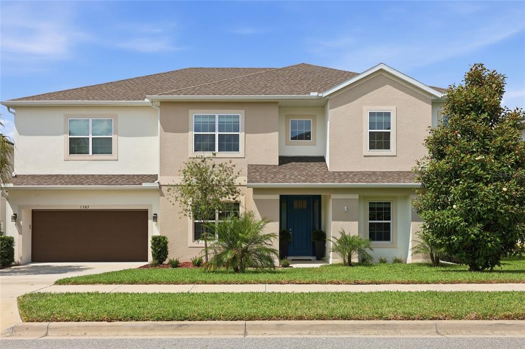 A two-story suburban house with a tan stucco exterior, brown roof, and a blue front door — 1383 WATERVIEW RIDGE CIRCLE, APOPKA, FL