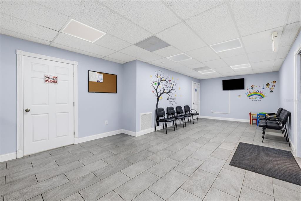 A waiting room with light blue walls, tiled floors, black chairs, and a wall mural — 507 E DR MARTIN LUTHER KING JR BOULEVARD, TAMPA, FL