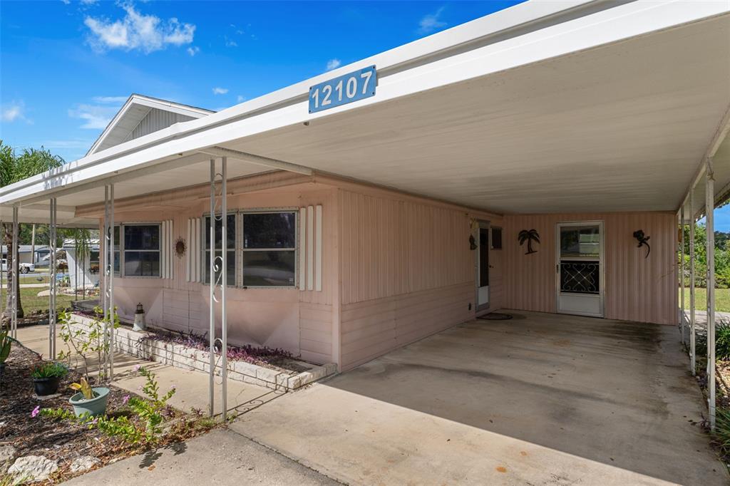 A pink mobile home features a large attached carport and a concrete driveway — 12107 ELDORADO AVENUE, BROOKSVILLE, FL