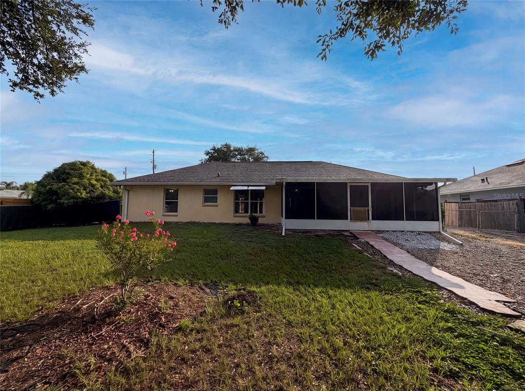 The rear exterior of a single-story house features a screened-in porch and a grassy yard — 314 DUPONT CIRCLE, HOWEY IN THE HILLS, FL
