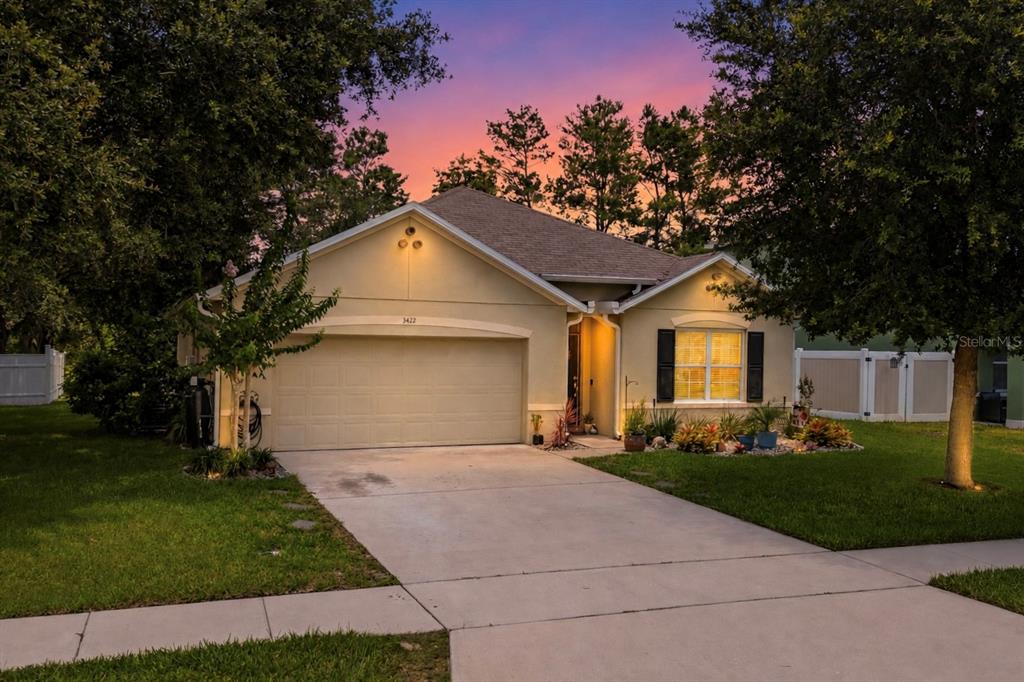 A single-story house with a beige stucco exterior, a two-car garage, and a concrete driveway — 3422 BERKSHIRE WOODS TERRACE, DELTONA, FL