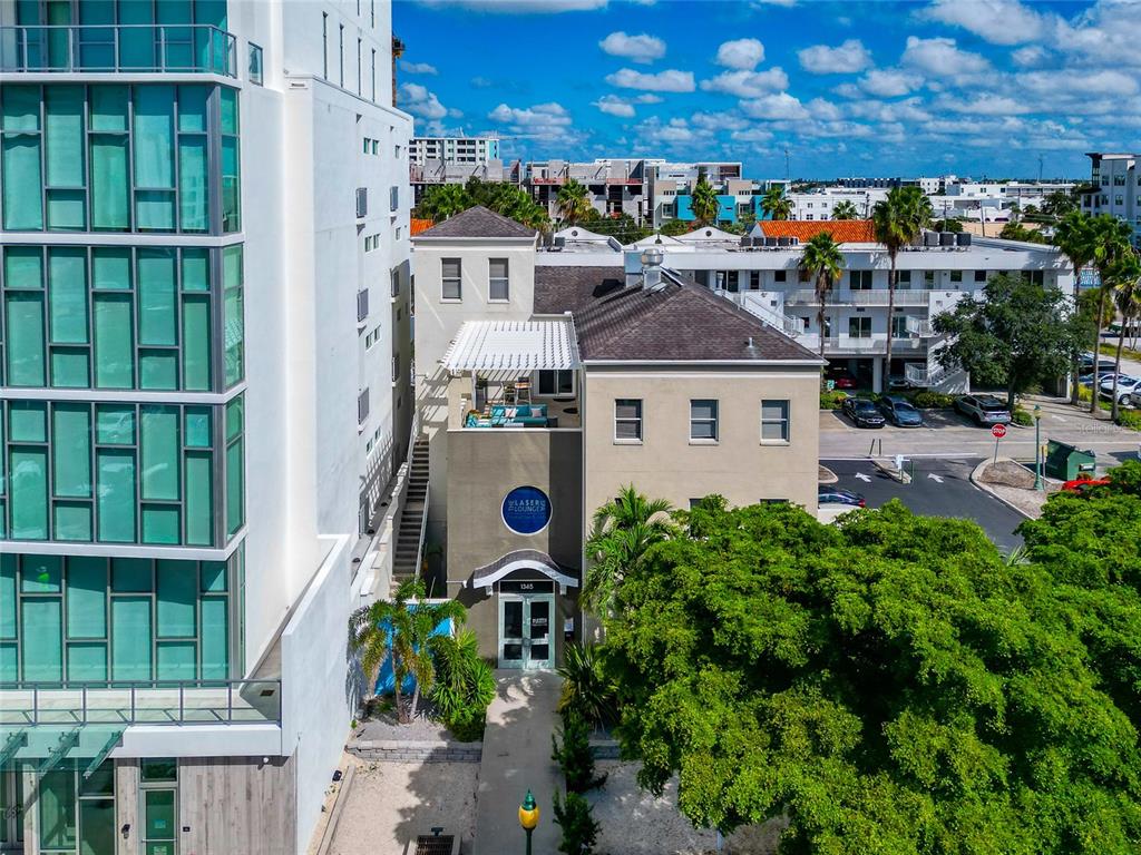 An aerial view shows a multi-story building with a blue circular sign and rooftop patio — 1345 2ND STREET, SARASOTA, FL